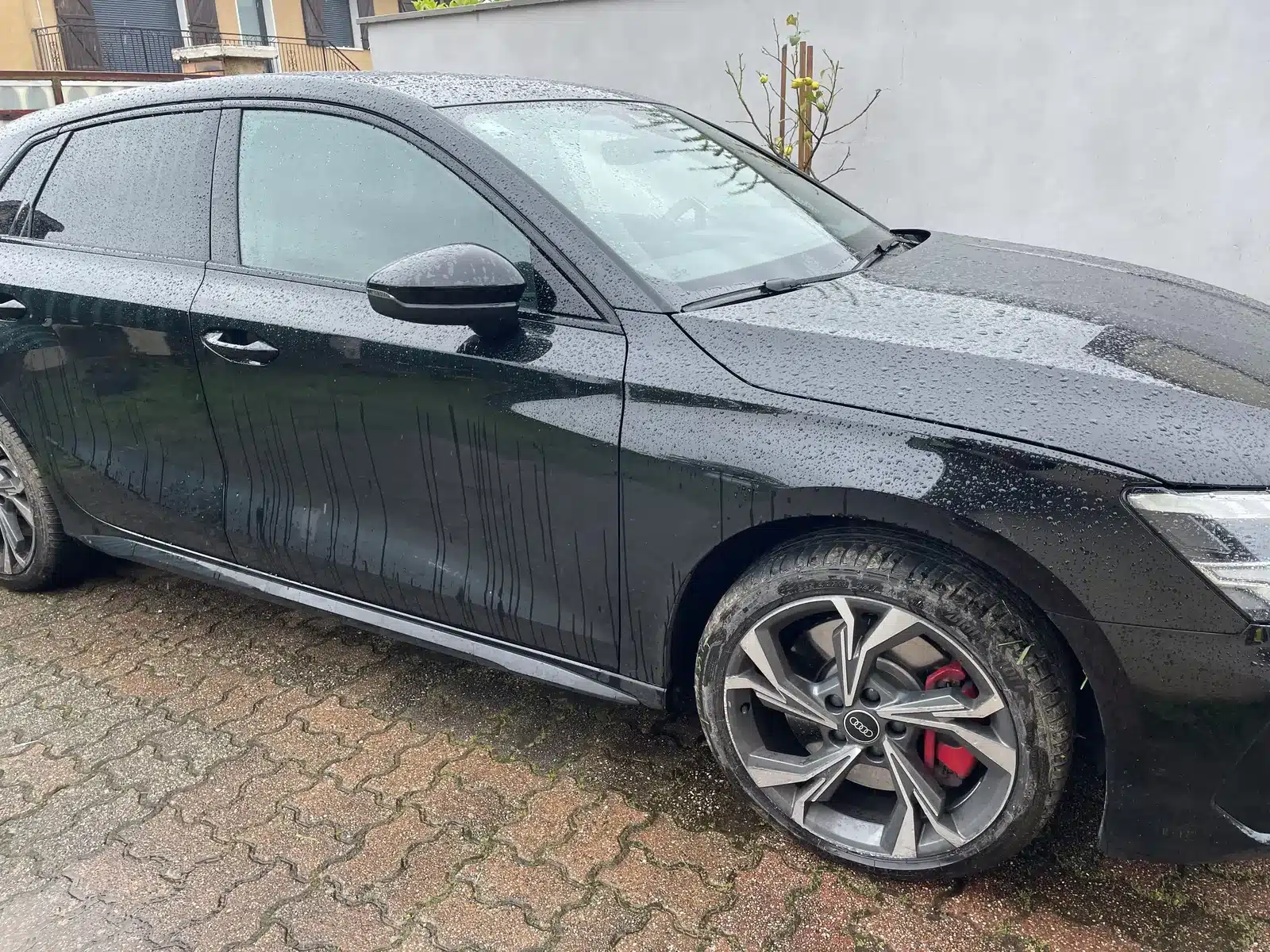 Berline noire en cours de rinçage lors d'un lavage à domicile